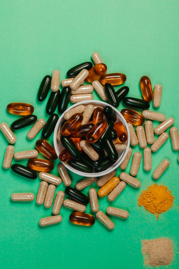 Top view of various colored capsules and powders on a green surface.