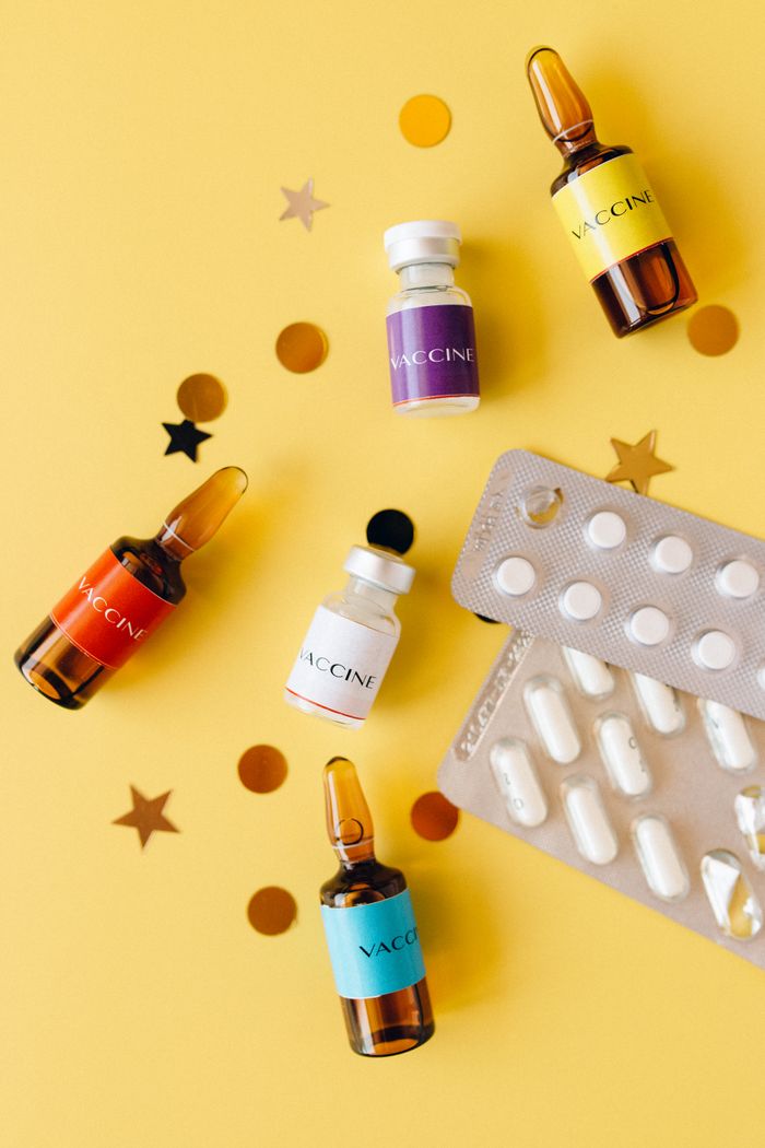Vibrant still life featuring vaccine vials and pills on a yellow background, ideal for healthcare themes.